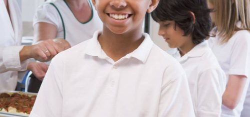 Smiling kid holding plate of healthy school lunch